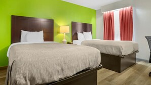 Une chambre d’hôtel avec deux lits, un mur vert, une fenêtre avec des rideaux rouges et une table de chevet avec une lampe.