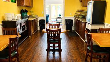 Una cocina con gabinetes de madera, una mesa de comedor, sillas y un refrigerador.