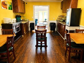 A kitchen with wooden cabinets, a dining table, chairs, and a refrigerator.