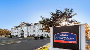 Señal de hotel de Howard Johnson Inn by Wyndham, con un edificio grande al fondo.