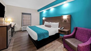 Una habitación de hotel con cama, escritorio, silla y mesita de noche con teléfono.