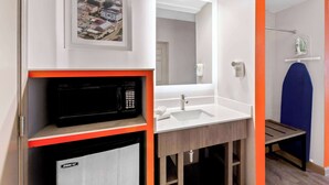 Un baño moderno con un lavamanos blanco, un espejo, un microondas y un mueble pequeño.