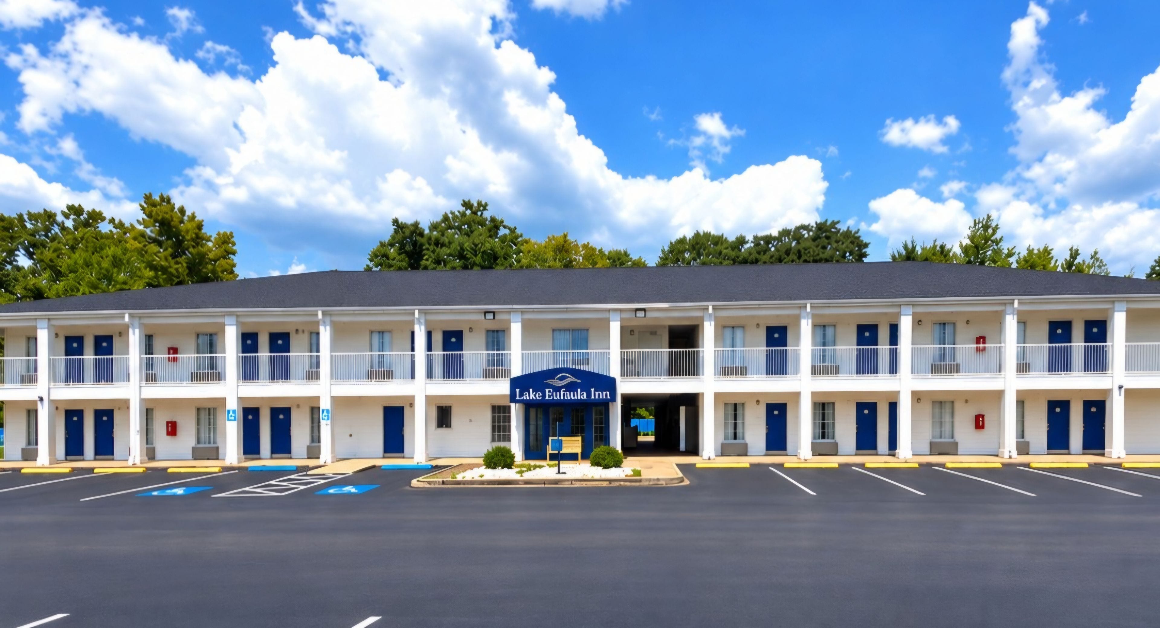 Ein Motel mit Mittelportal, mehreren Zimmern und einem Parkplatz.
