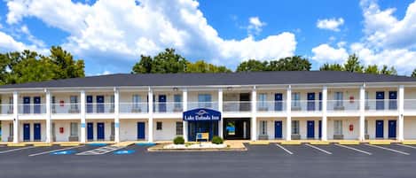 Ein Motel mit Mittelportal, mehreren Zimmern und einem Parkplatz.