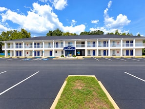 A motel with a central entrance, multiple balconies, and a parking lot.