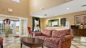 A spacious lobby with a red floral sofa, a wooden coffee table, and a patterned rug. - Baymont by Wyndham Eufaula (Eufaula)