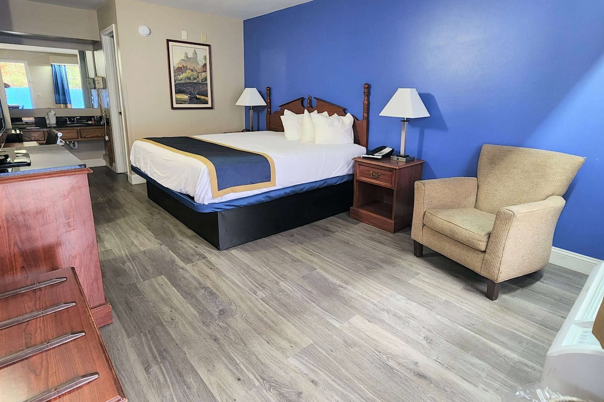 A hotel room with a bed, bedside tables, a chair, a desk, and a mirror.