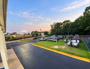 Un parking où sont stationnés divers véhicules, notamment des voitures et des bateaux, ainsi qu’une zone herbeuse avec des arbres.
