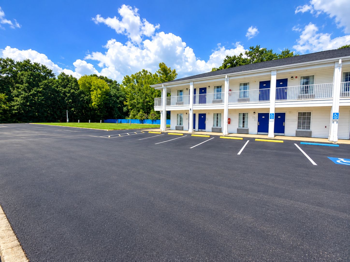 A two-story motel with a parking lot and a blue handicap parking sign.