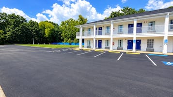 A two-story motel with a parking lot and a blue handicap parking sign.