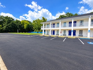 Un motel à deux étages, doté d’un parking et d’un panneau bleu indiquant les places de stationnement réservées aux personnes handicapées.