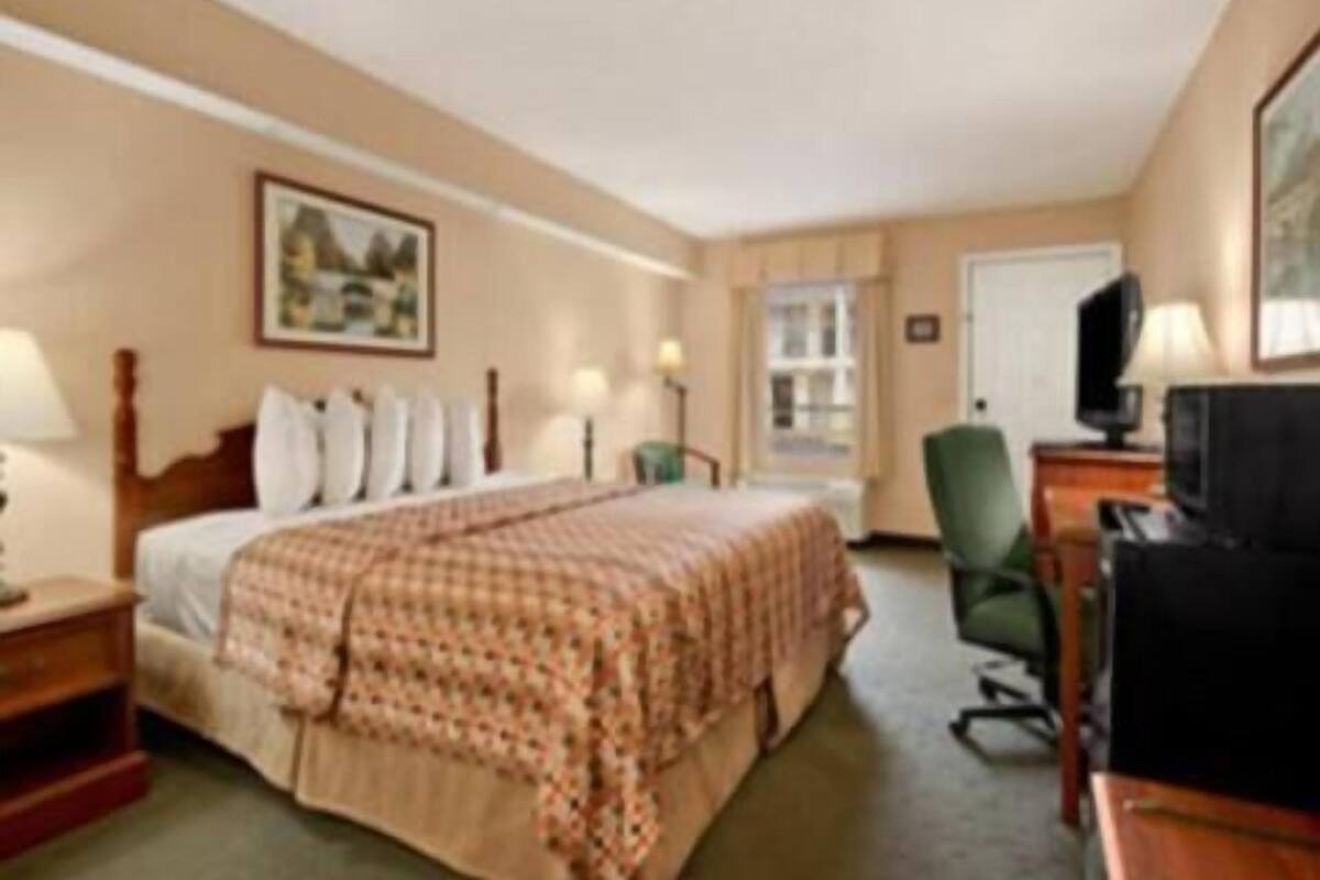 Une chambre d’hôtel avec un lit, un bureau, une chaise, une télévision et une fenêtre.