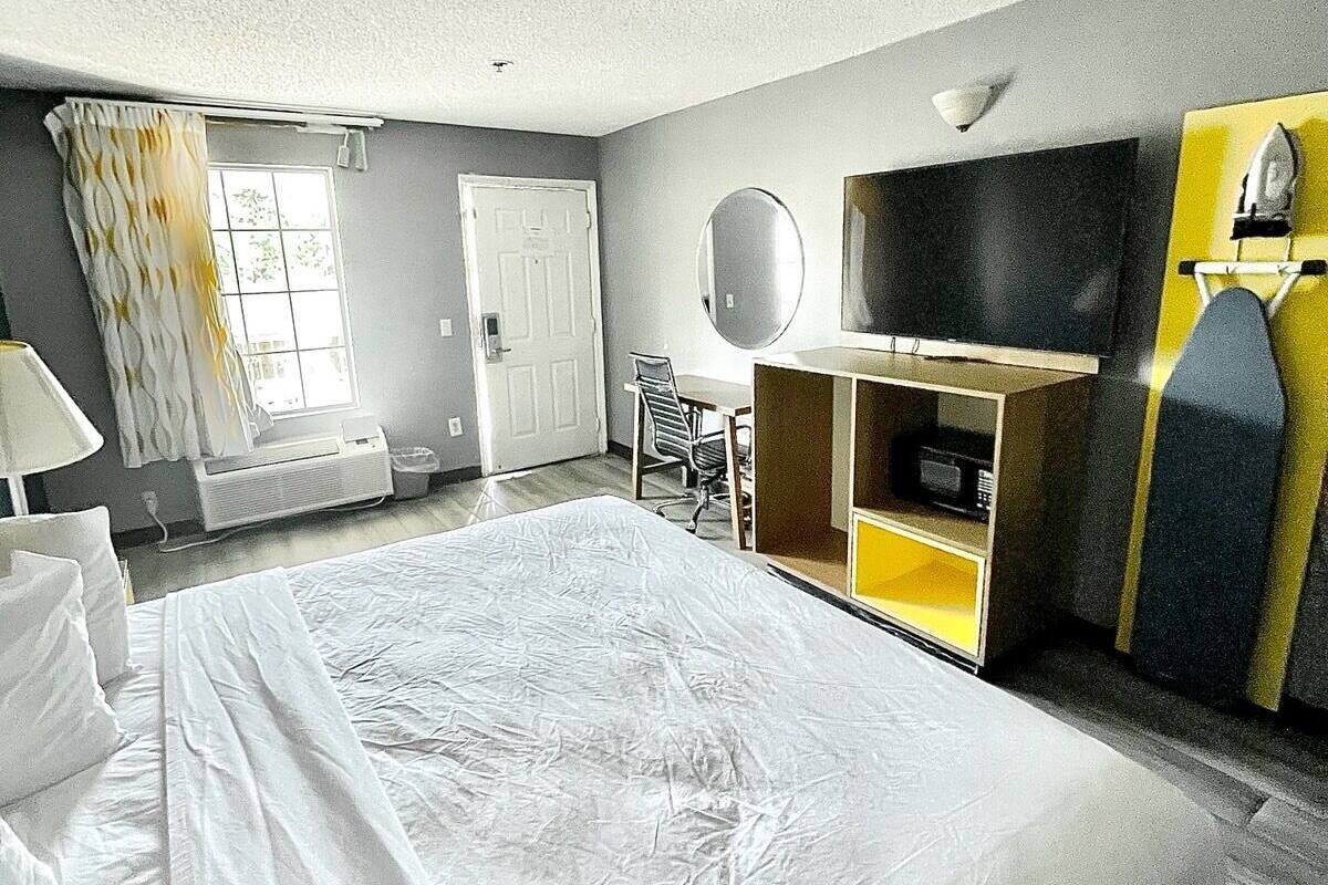 Une chambre d’hôtel avec un grand lit, un bureau, une chaise, un miroir et un téléviseur.