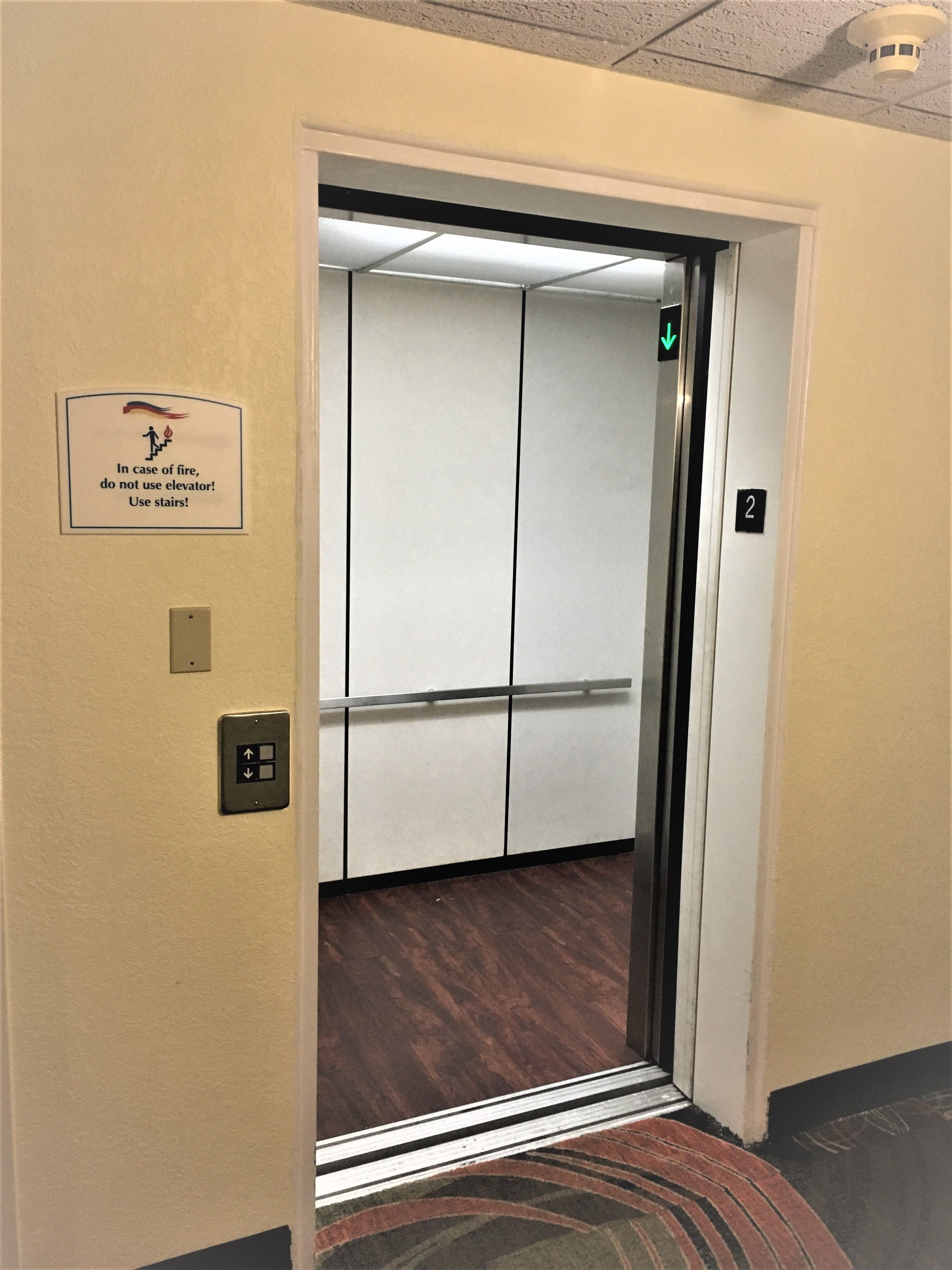 Een liftinterieur met een bord dat vraagt de trap te gebruiken bij brand.