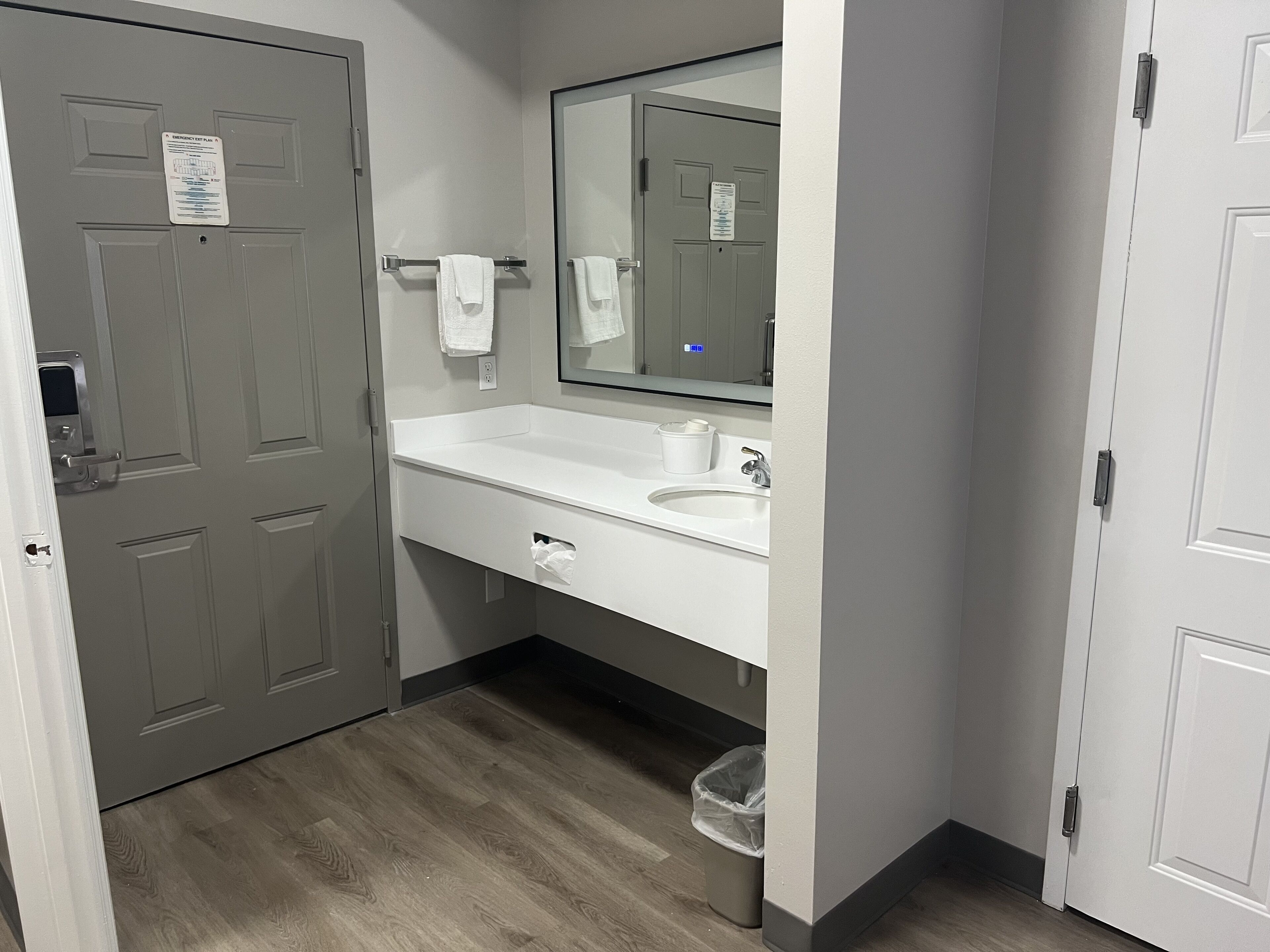 A bathroom with a white sink, mirror, and towel rack.