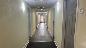 A long, narrow hallway with carpeted floors and doors on both sides.