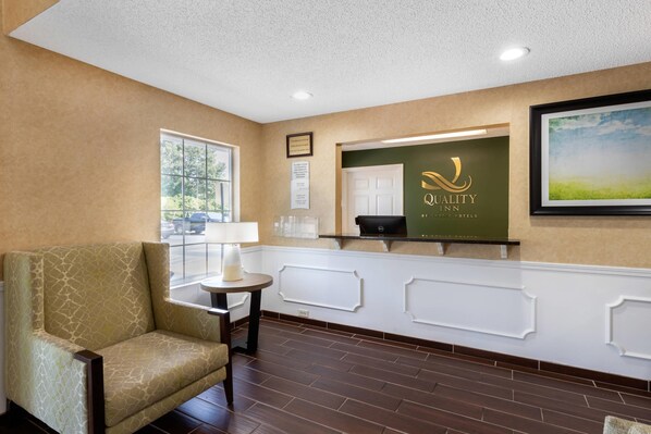 A reception area with a reception desk, a chair, a lamp, and a framed picture on the wall.