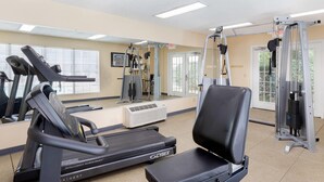 Un gimnasio con cintas de correr, un banco de pesas y máquinas de ejercicio.