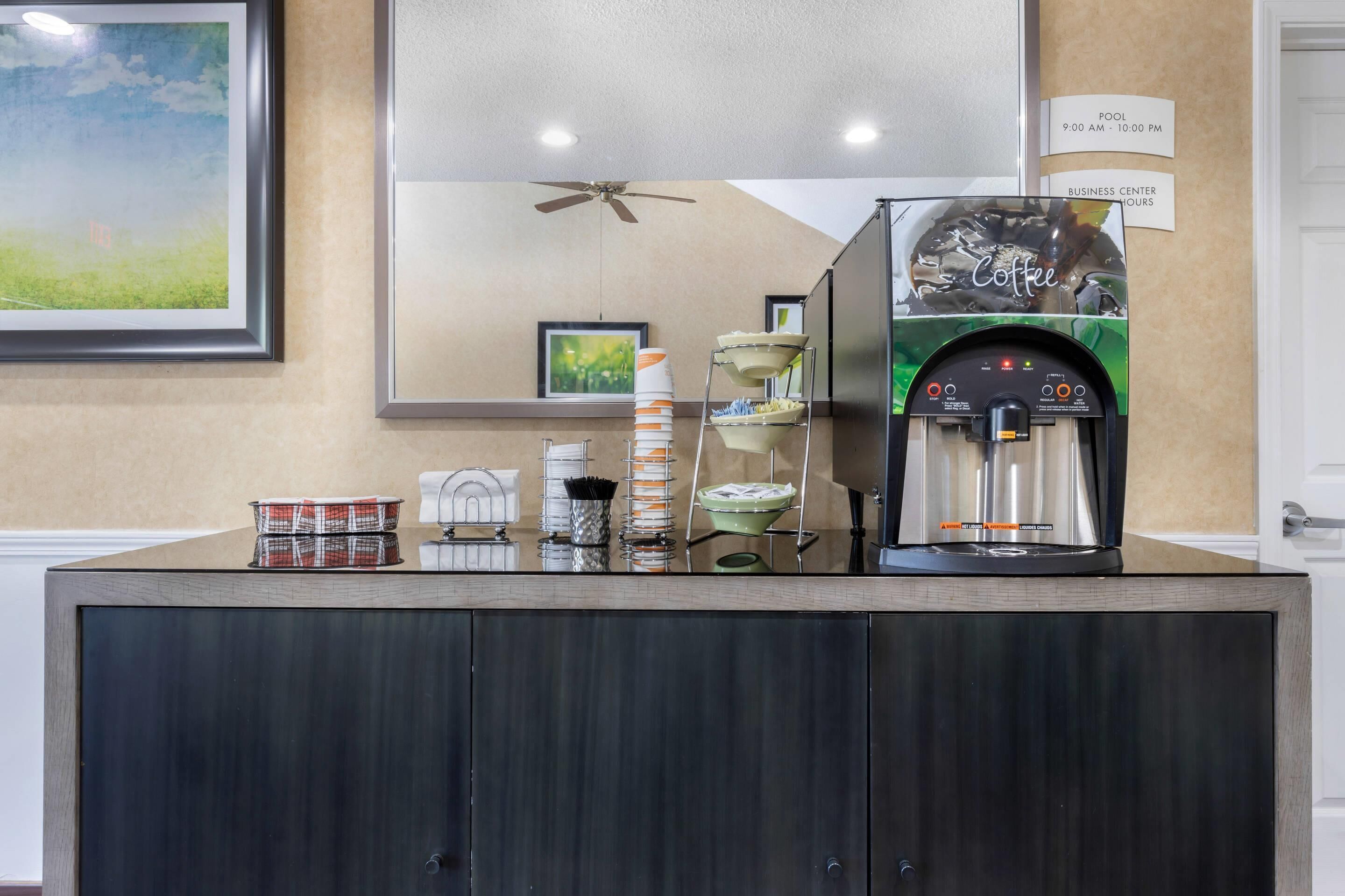 Un espace dédié au café, équipé d’une machine à café, de tasses et d’un panneau affichant le menu.