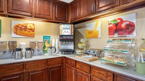 Una barra de desayuno con exhibición de waffles, estación de café y exposición de frutas.