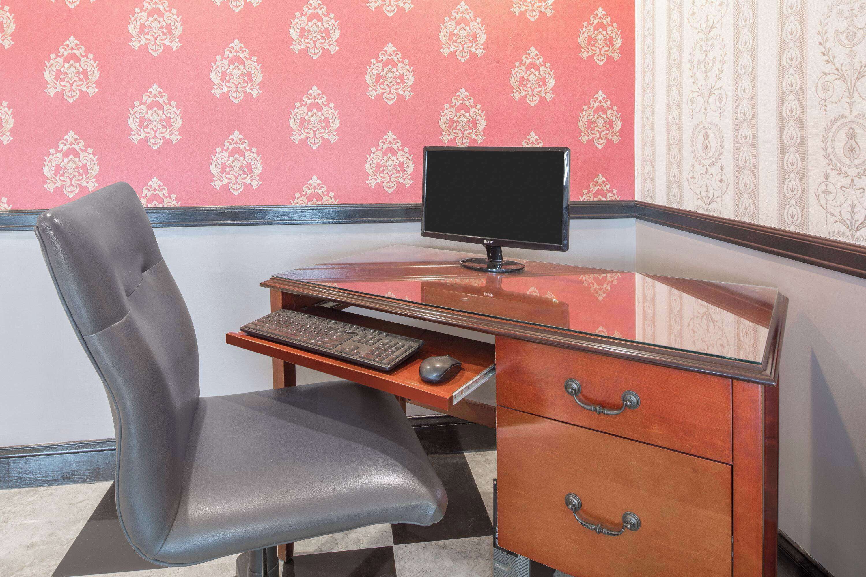 A wooden desk with a computer, a chair, and a keyboard.