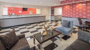 Un vestíbul d'hotel amb una taquilla d'eixida, parets amb motius decoratius i un paviment a escac.