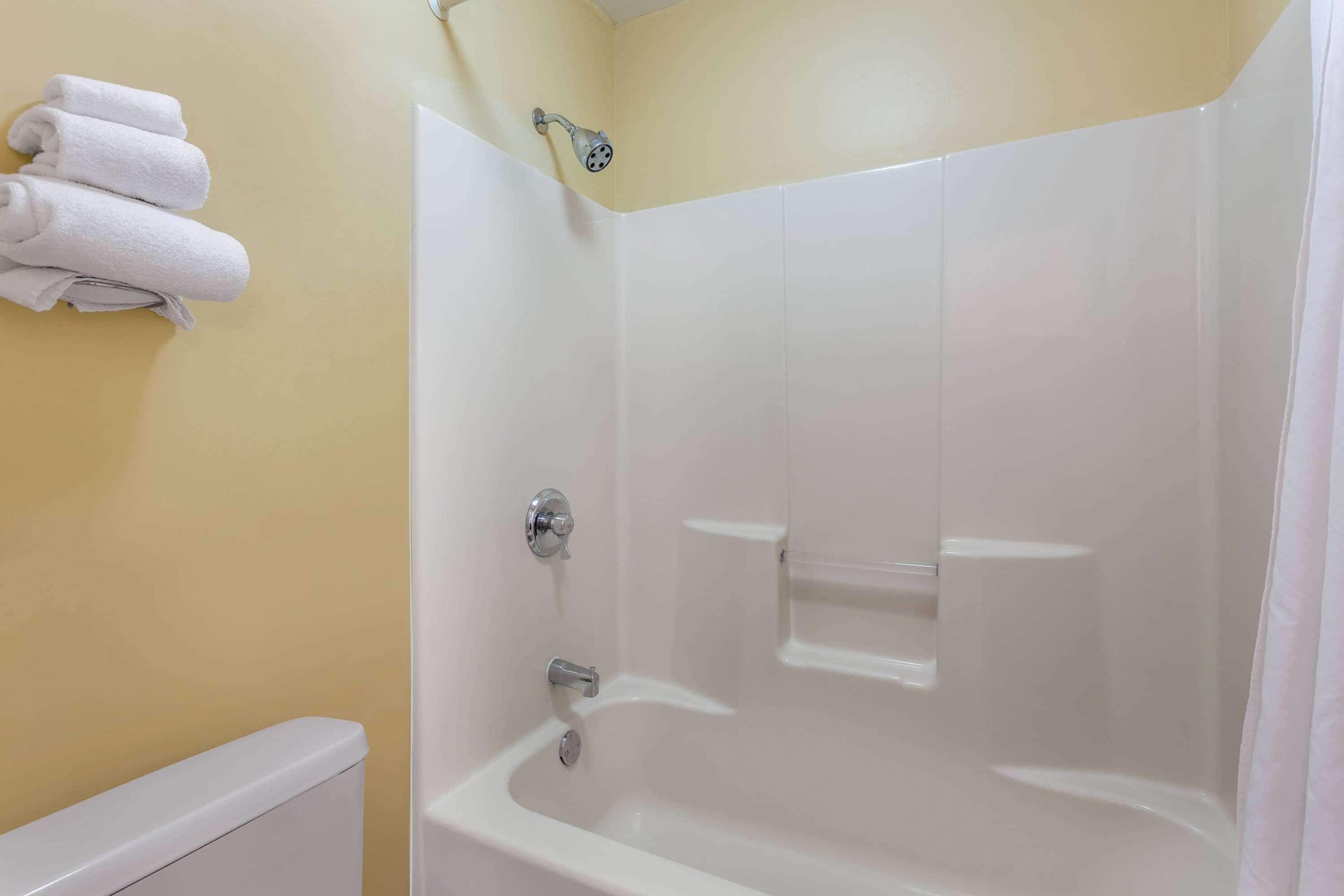 A bathroom with a bathtub, a shower, and a toilet. There are towels hanging on the wall.