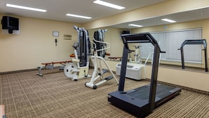 Un gimnasio con equipo de ejercicio, una cinta de correr y un espejo.