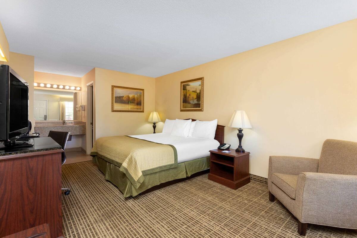 Una habitación de hotel con cama, escritorio, silla y televisor.