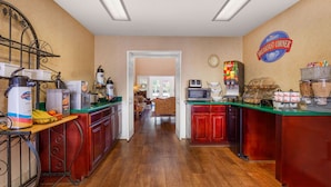 Un espacio para desayunar con mostrador, máquinas de café y un letrero que dice 'Breakfast Corner'.