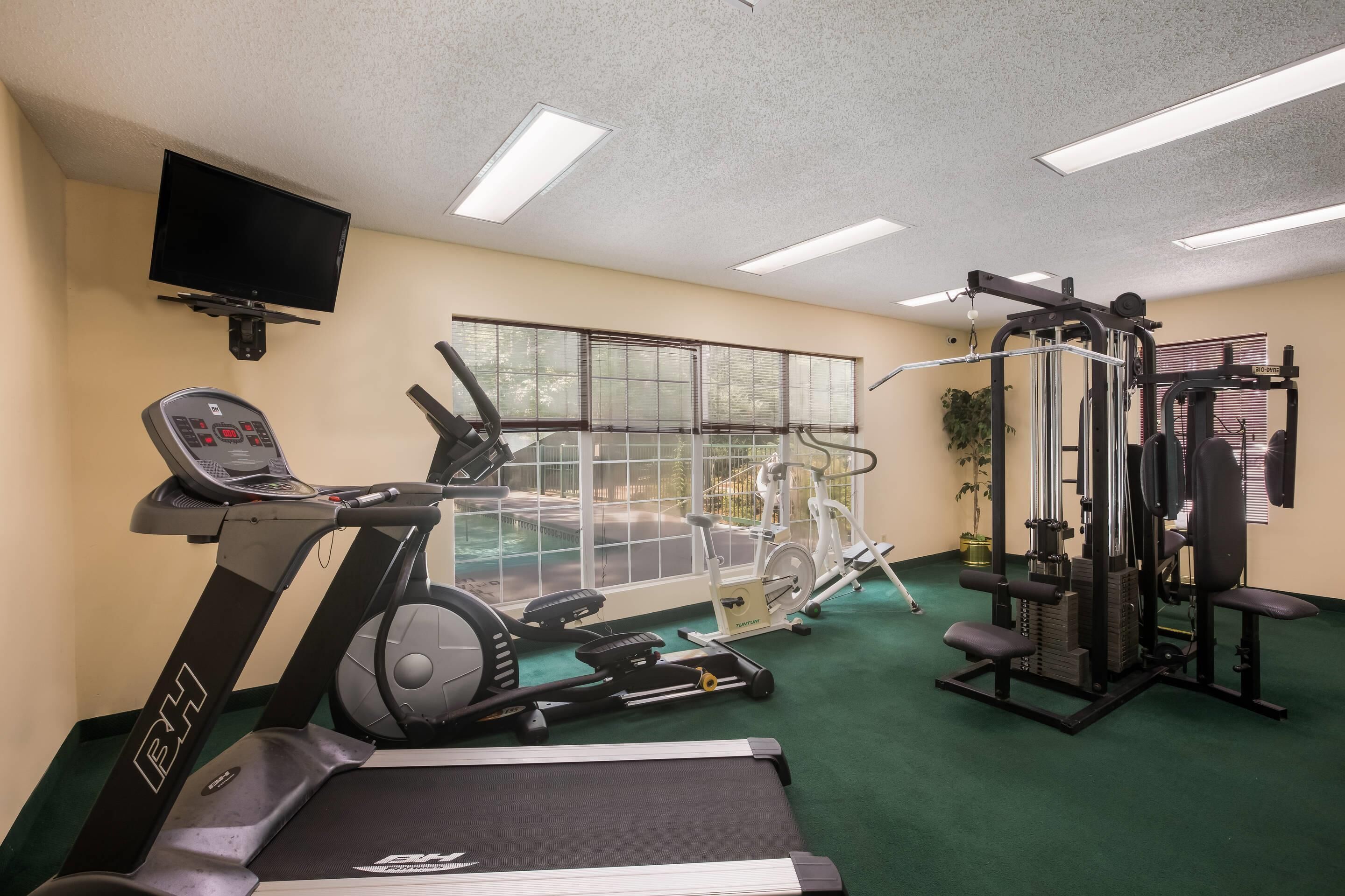 Une salle de sport équipée de tapis de course, de vélos elliptiques et d’appareils de musculation.