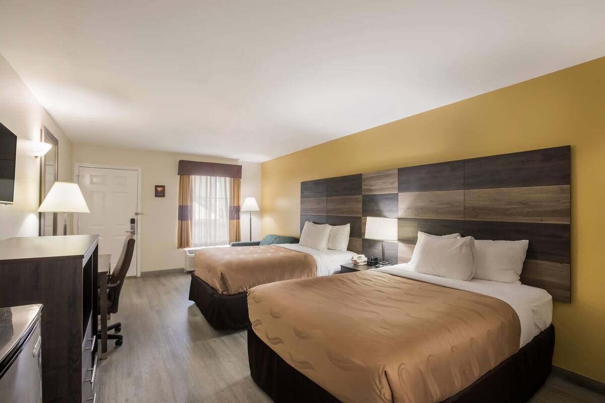 Ein Hotelzimmer mit zwei Betten, einem Schreibtisch und einem Sessel.