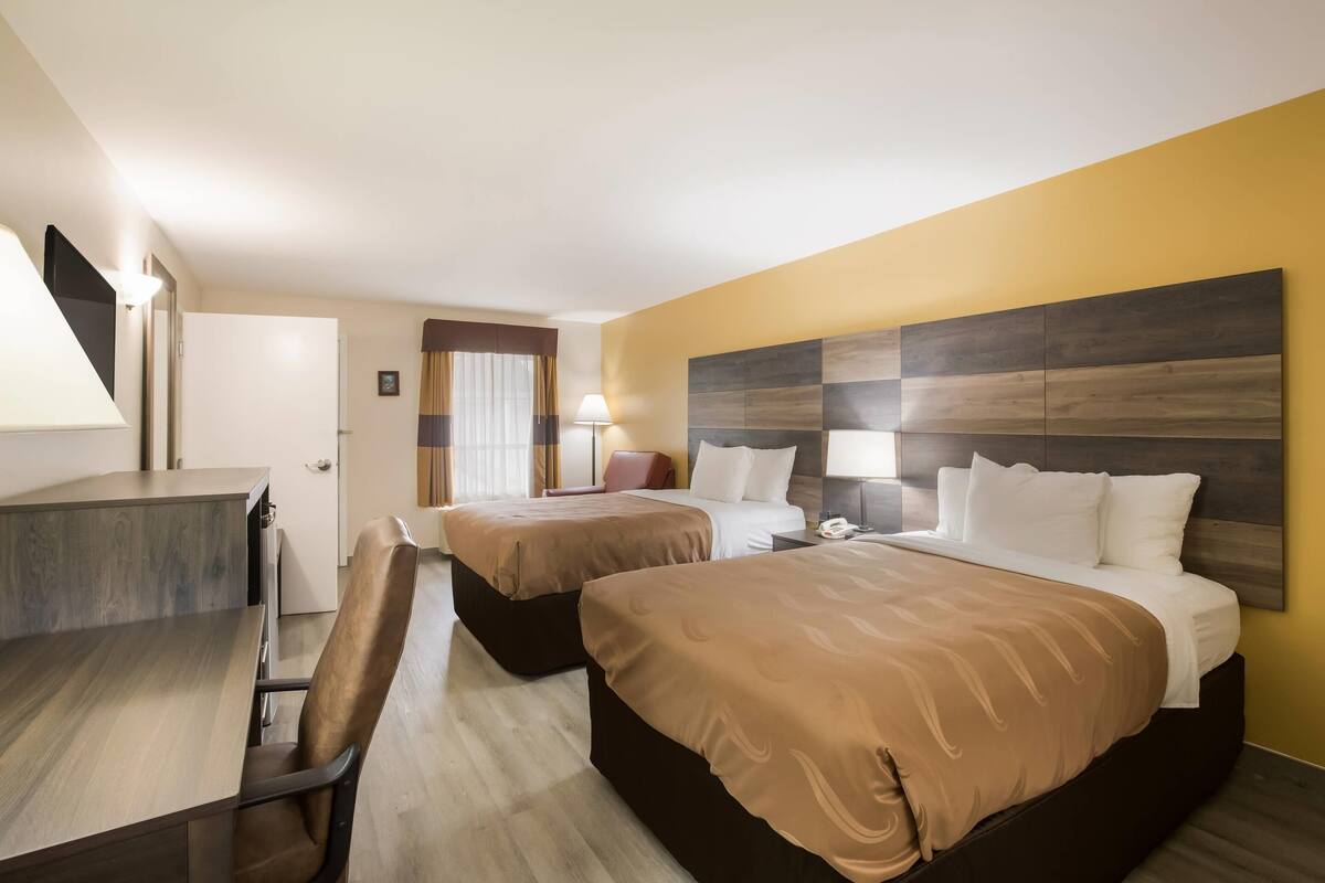 Ein Hotelzimmer mit zwei Betten, einem Schreibtisch und einem Sessel.
