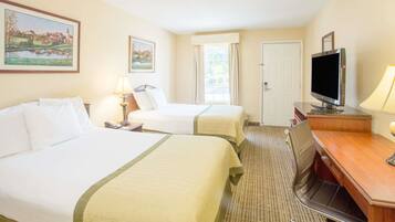 A hotel room with two beds, a desk, a television, and a window with curtains.