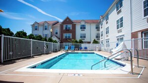 A rectangular swimming pool with a white deck, surrounded by a white fence, and blue lounge chairs. - Towneplace Suites By Marriott Streetsboro (Streetsboro)