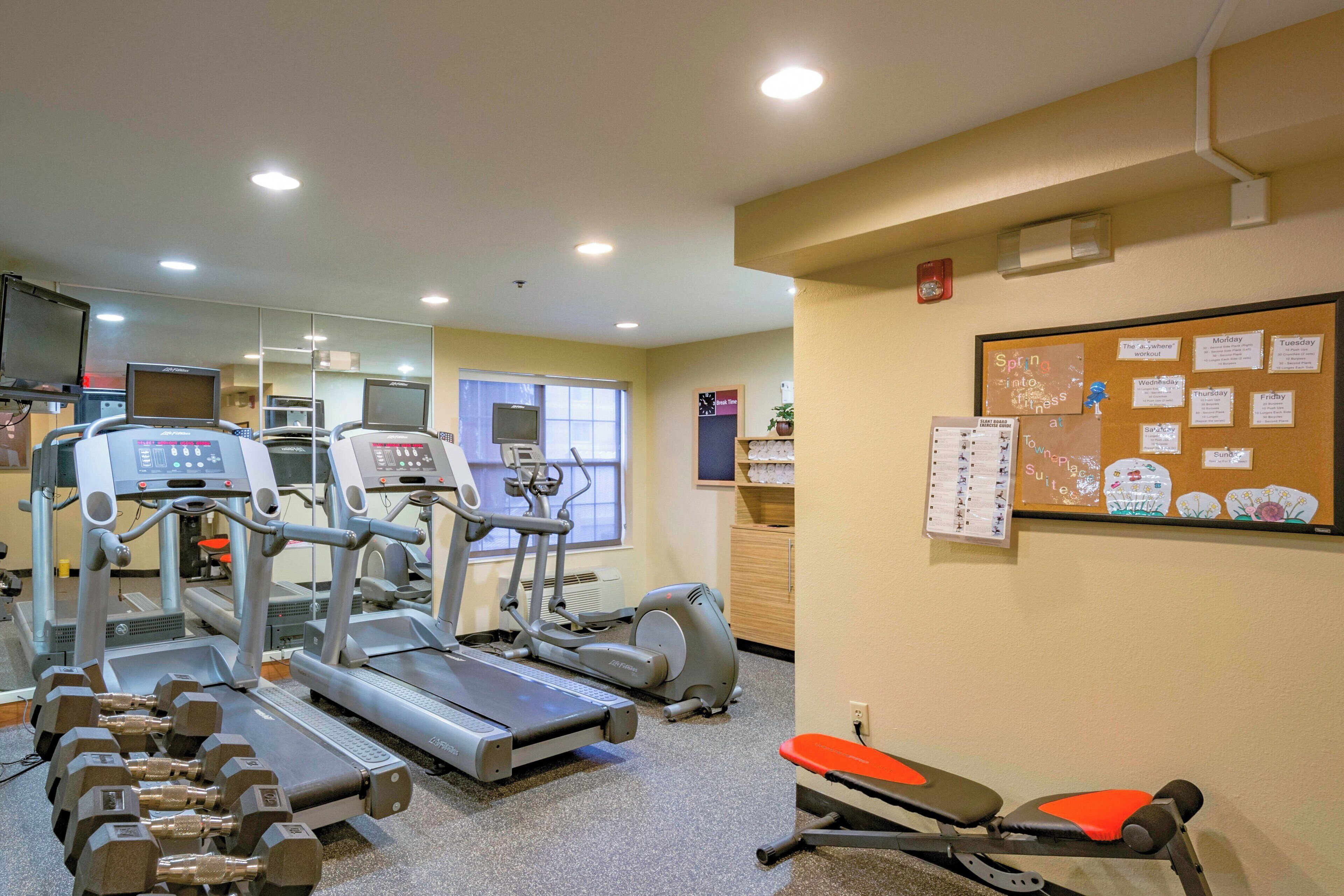 Et fitnesscenter med løbebånd, crosstrainere og vægte.