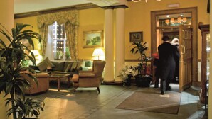 A lobby with a sofa, chairs, a table, and potted plants.