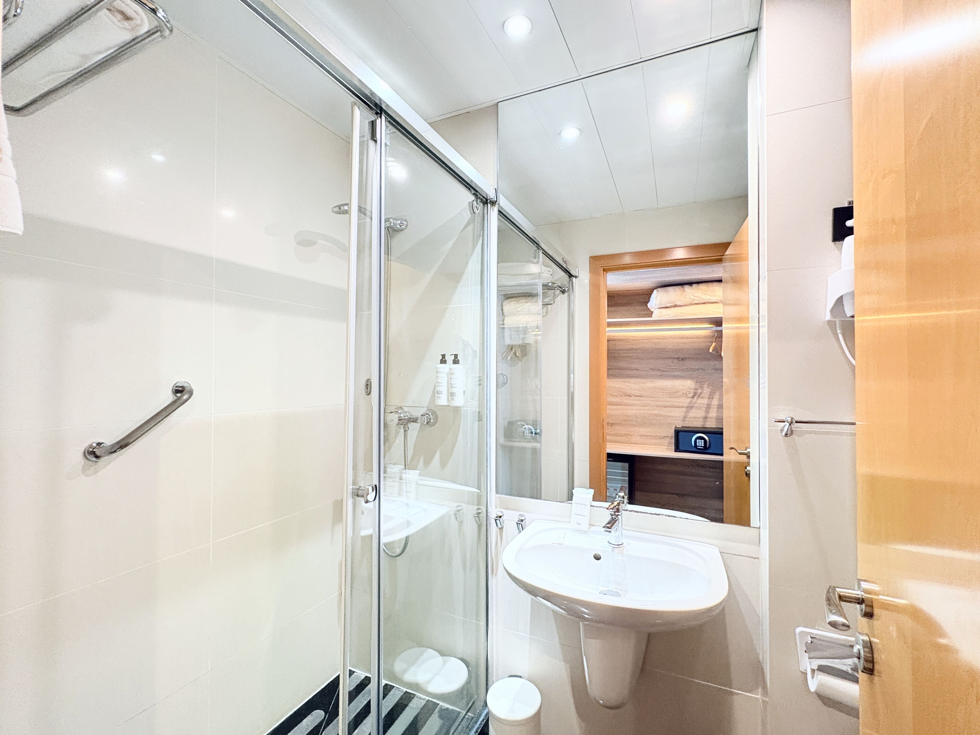 Un baño moderno con cabina de ducha de vidrio, un lavabo y un mueble de tocador de madera.