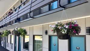 A row of hotel rooms with teal doors and windows, each with a number label. - Travelodge Inn & Suites by Wyndham Missoula University Park (Missoula)