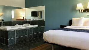 A hotel room with a bed, a bathroom with a sink, and a mirror. - Travelodge Inn & Suites by Wyndham Missoula University Park (Missoula)