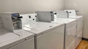 A row of white laundry machines in a clean, modern laundry room with a wooden floor. - Travelodge Inn & Suites by Wyndham Missoula University Park (Missoula)