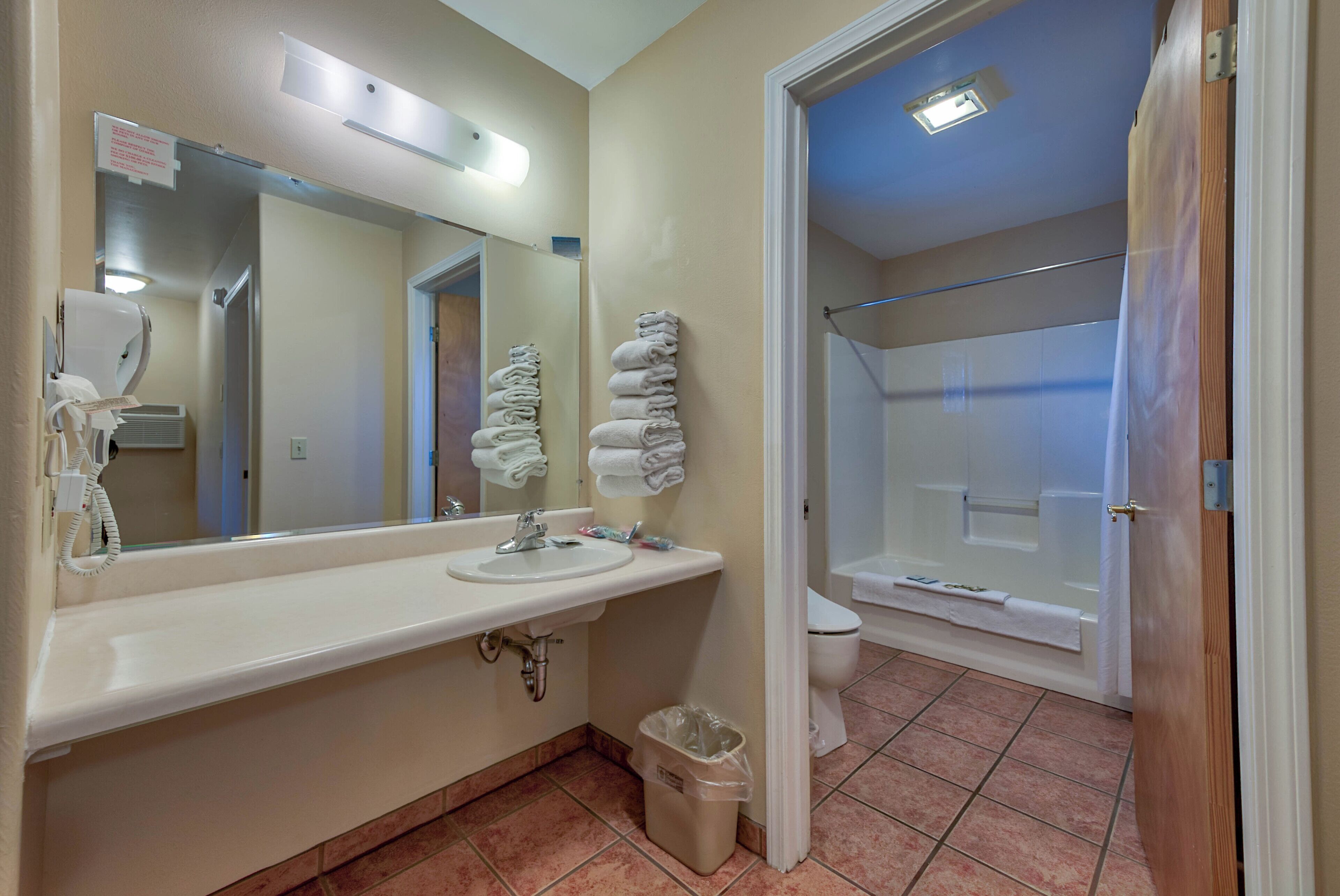 Une salle de bain avec un lavabo, un miroir et des serviettes pliées.