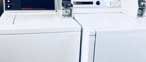 A row of commercial washers in a utility room.