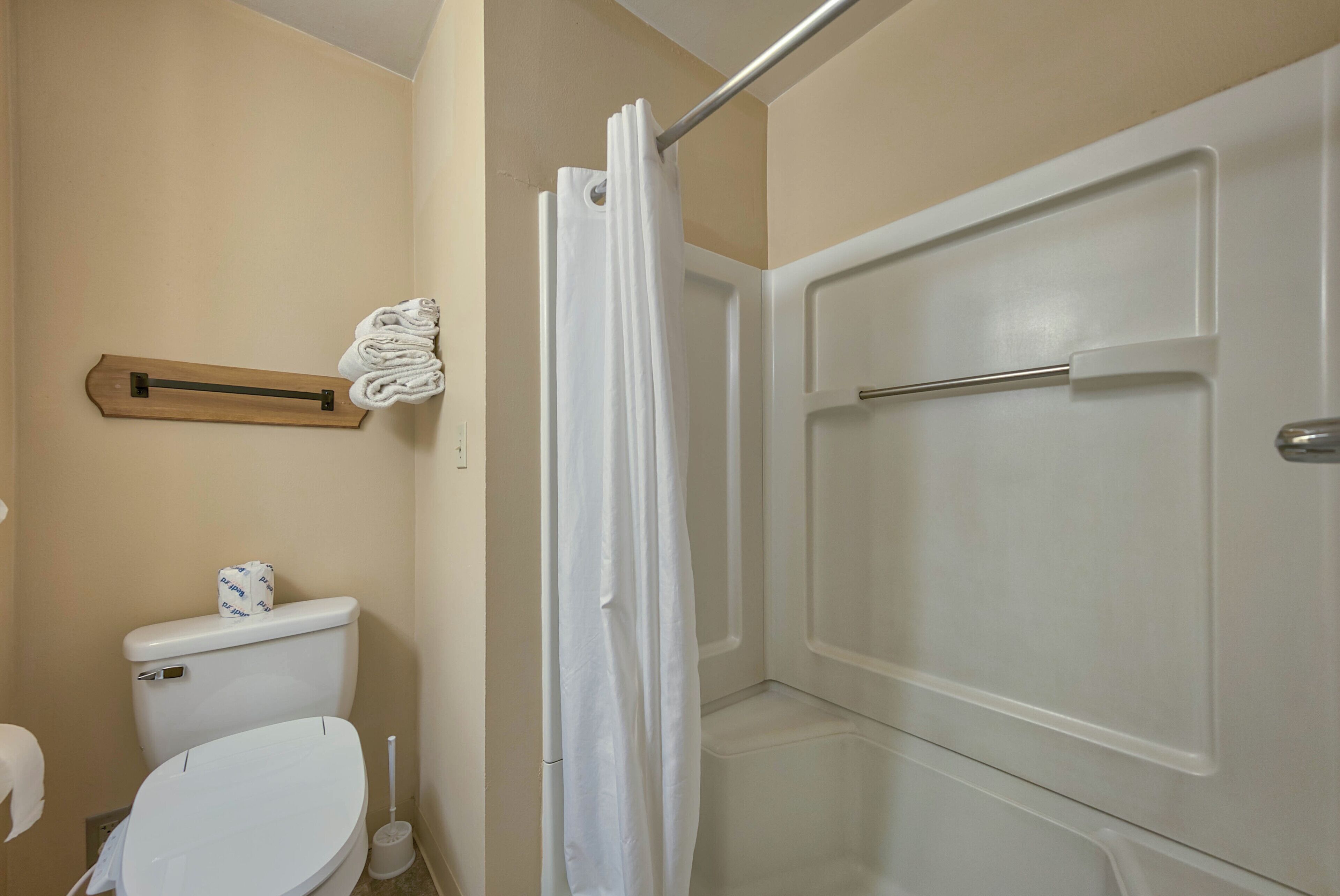 A bathroom with a toilet, a shower curtain, and a towel rack.