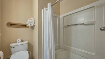 A bathroom with a toilet, a shower curtain, and a towel rack.