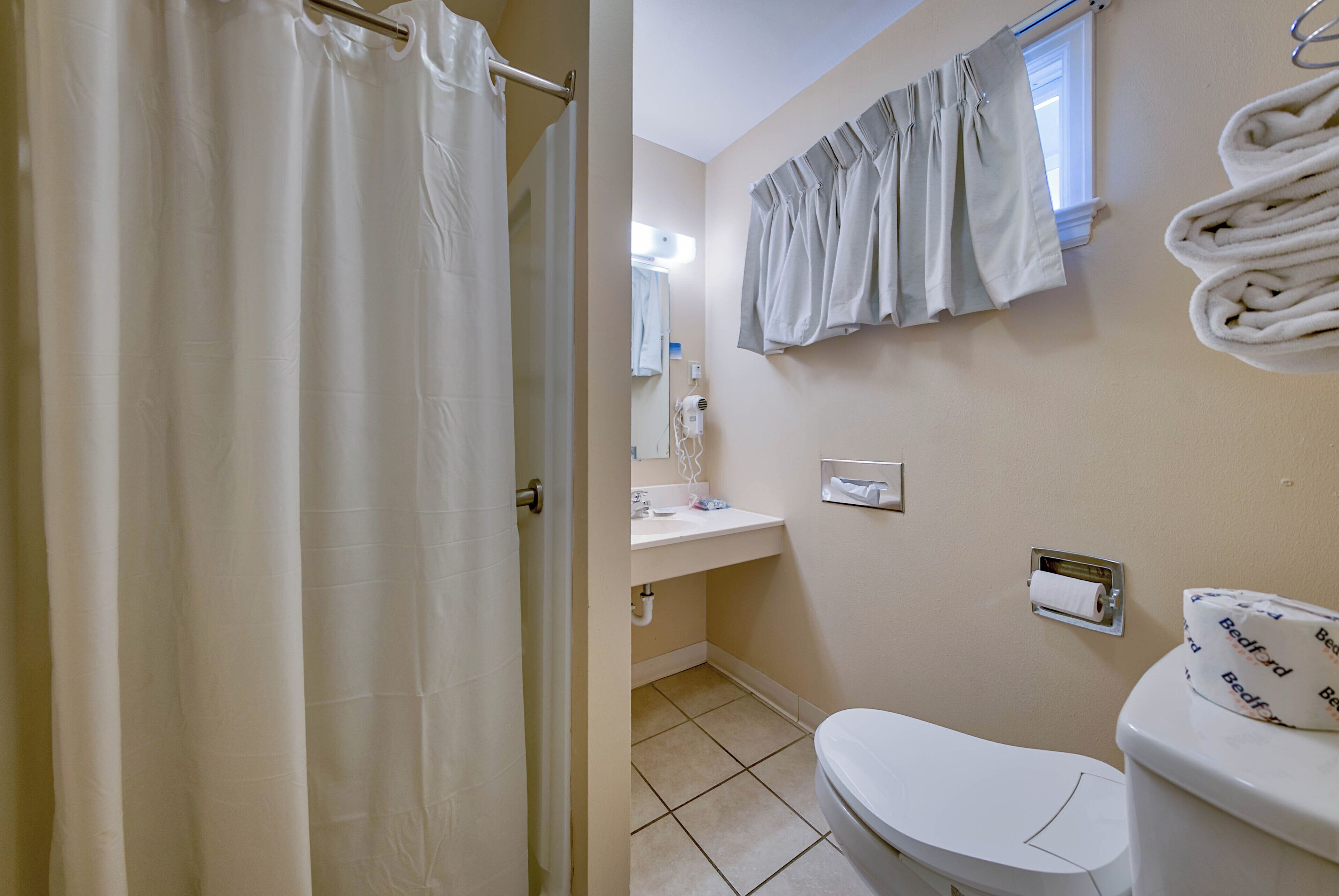 Une salle de bain équipée de toilettes, d’un lavabo et d’un rideau de douche.