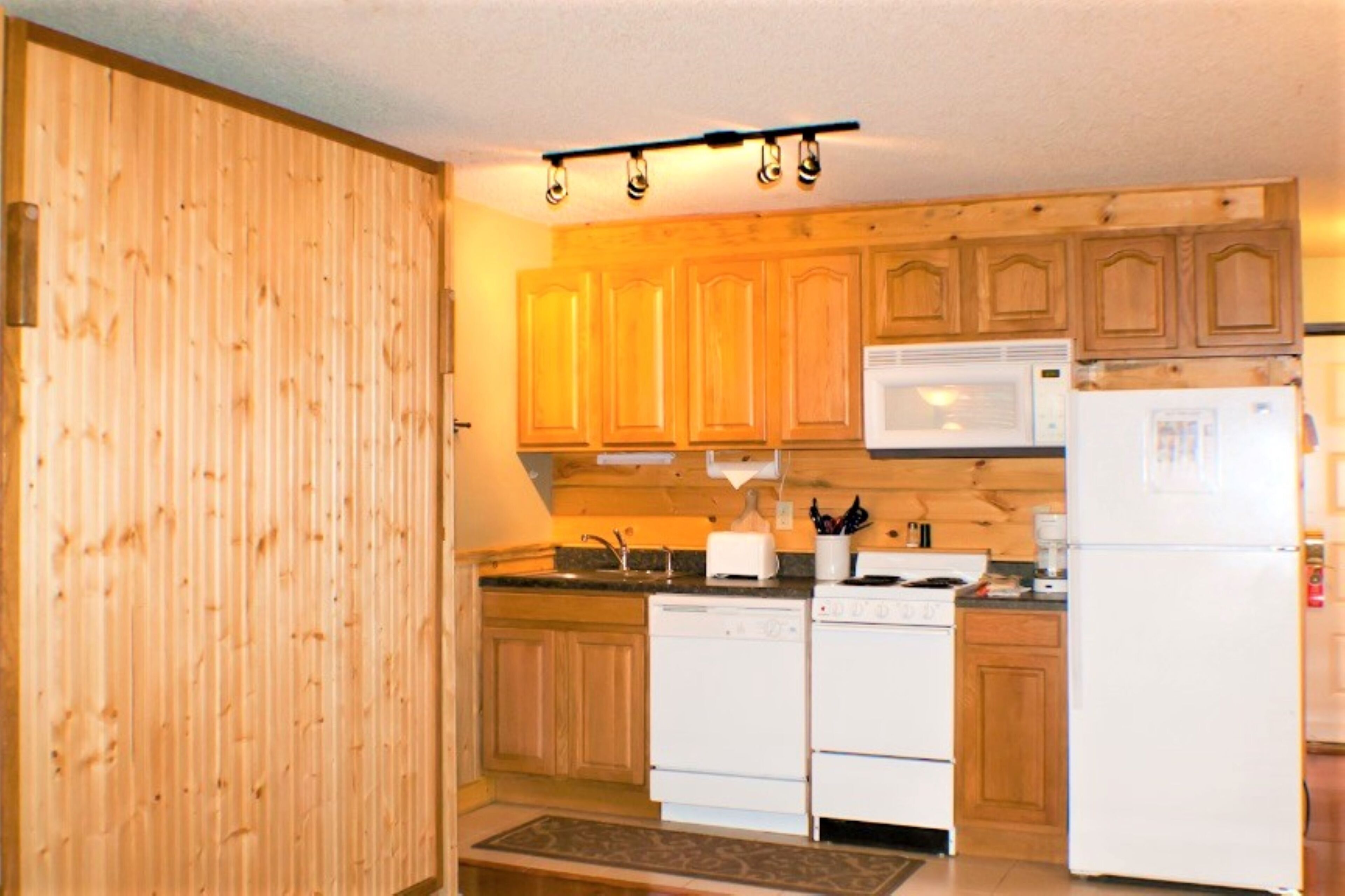 Una cocina con gabinetes de madera, microondas, estufa y refrigerador.