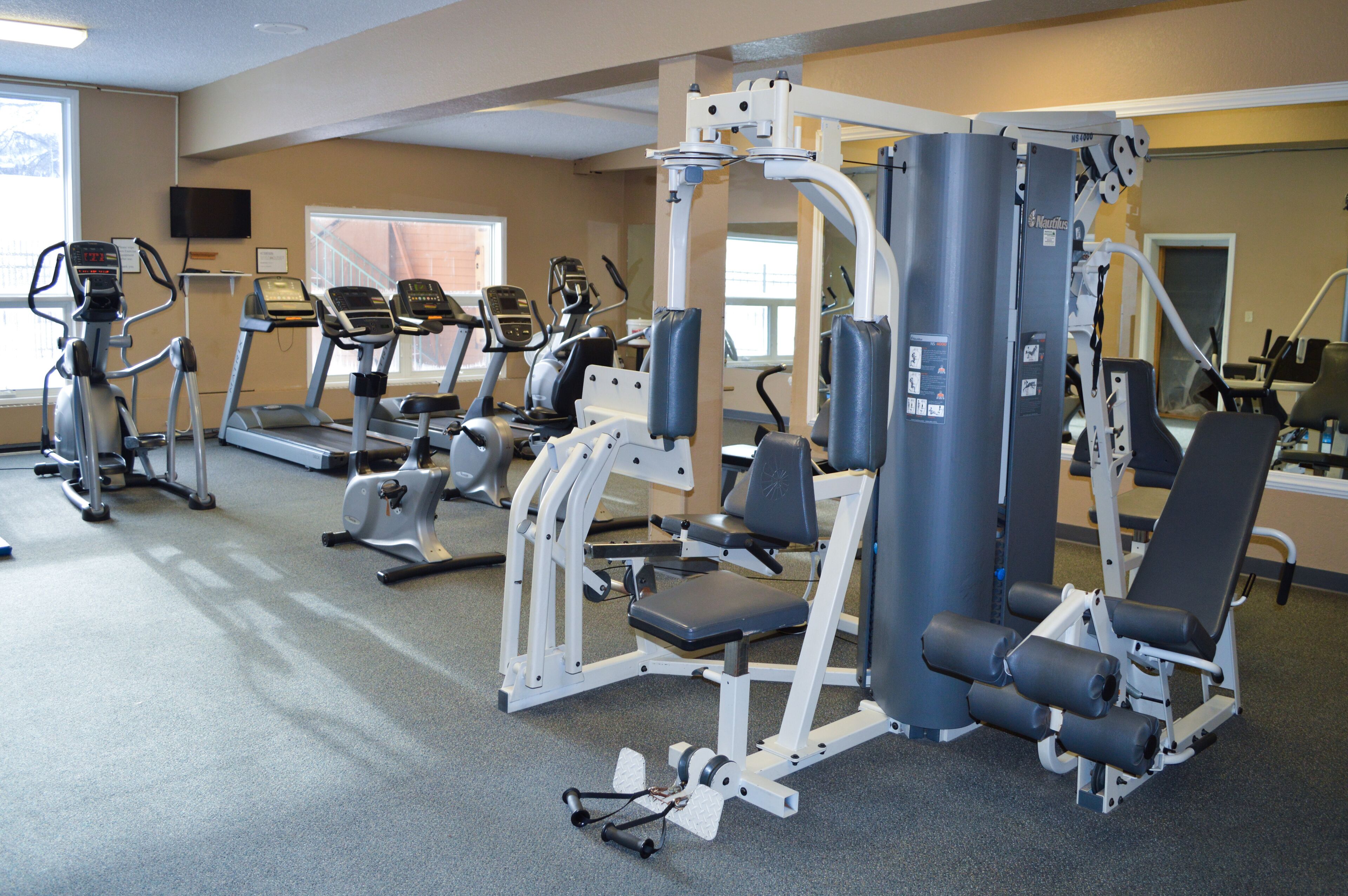 A gym with various exercise machines, including treadmills and weight stations.