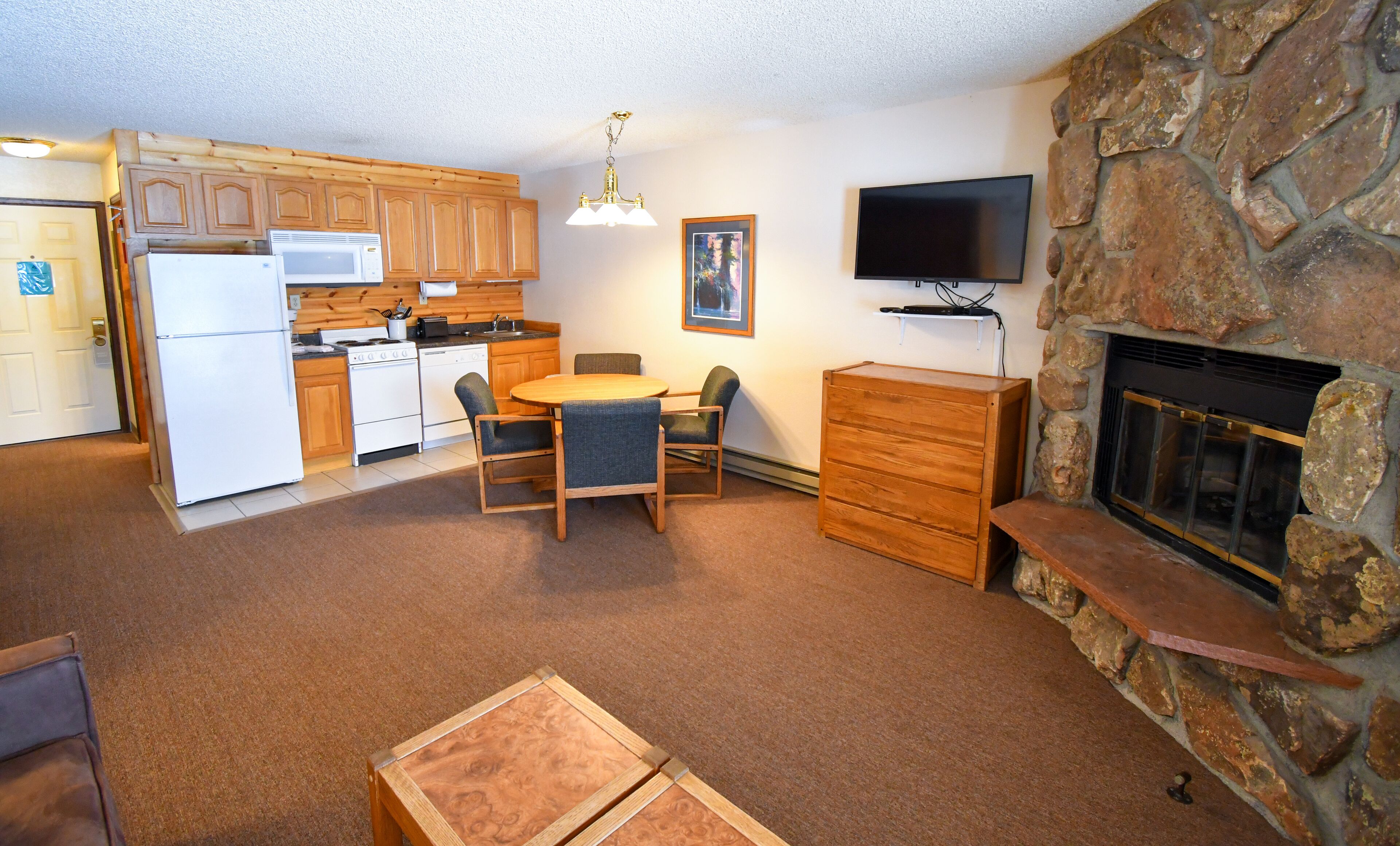 A compact living space with a kitchen, dining area, and a stone fireplace.