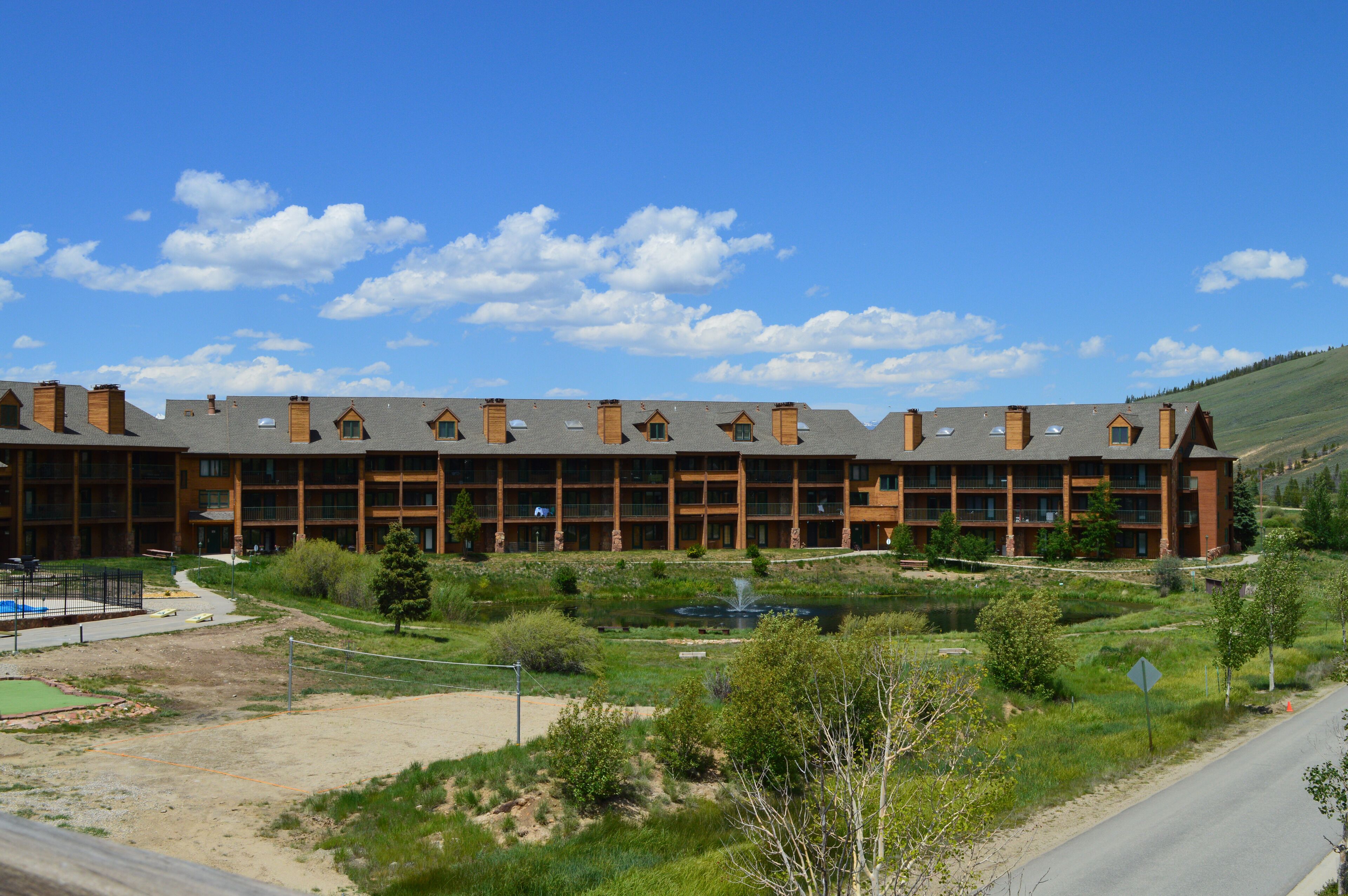 A large, multi-story hotel with a symmetrical facade, multiple balconies, and a landscaped courtyard with a pond.